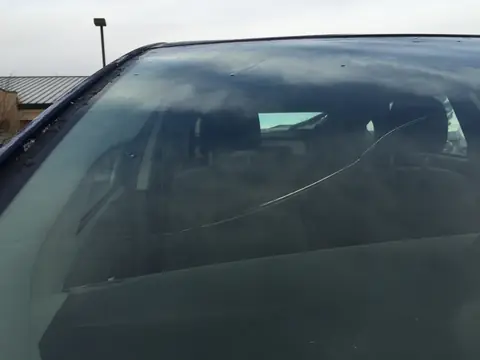 A long crack running across a car windshield