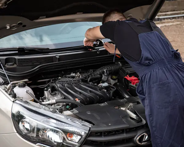 A technician leaning over the front of a silver SUV