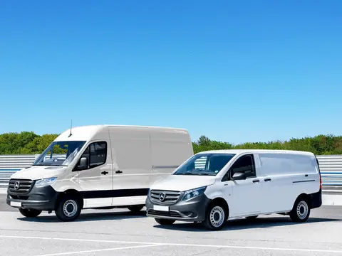 Two white work vans parked in a sunny lot
